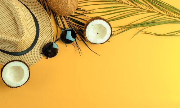 Summer composition. Tropical palm leaves, hat, glasses and broken coconut on a sandy background. The concept of the summer season, parties and heat. Flat lay, top view, copy space