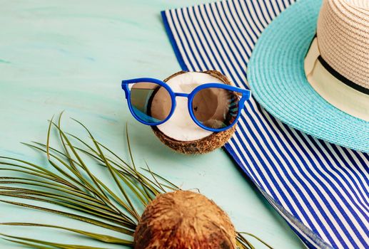 Summer composition or layout. Tropical palm leaves, hat, glasses, beach towel, coconut on a background of sea greens. The concept of the summer season and heat. Flat lay, top view, copy space