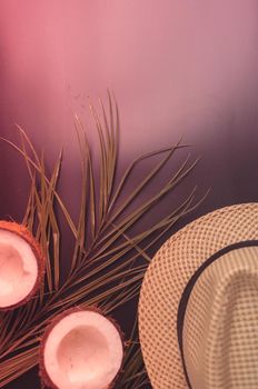 Summer composition with neon lights. Tropical palm leaves, hat, coconut on a dark background. The concept of the summer season, parties and heat. Flat lay, top view, copy space