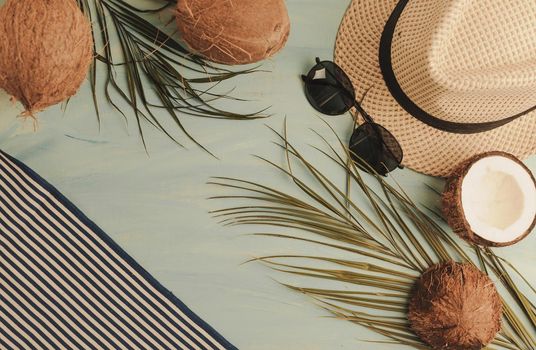 Summer composition or layout. Tropical palm leaves, hat, glasses, beach towel, coconut on a background of sea greens. The concept of the summer season and heat. Flat lay, top view, copy space