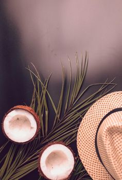 Summer composition with neon lights. Tropical palm leaves, hat, coconut on a dark background. The concept of the summer season, parties and heat. Flat lay, top view, copy space