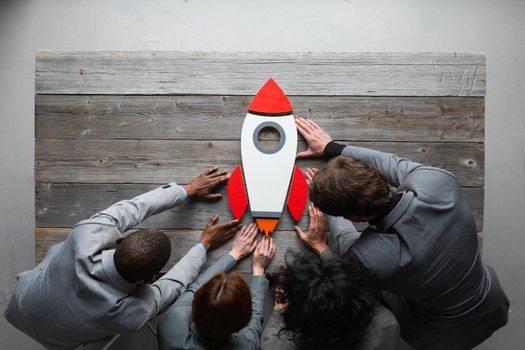 Creative business team sitting at table with startup rocket