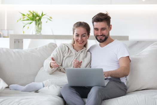 Portrait of mid adult couple relaxing in living room sitting together browsing internet on laptop computer