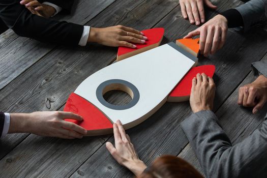 Creative business team sitting at table with startup rocket