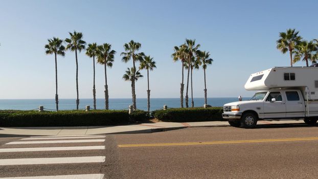 Motorhome trailer or caravan for road trip. Waterfront tropical palm trees and pacific ocean beach, Oceanside California USA. Beachfront vacations in camper van, RV motor home. Mobile home campervan.