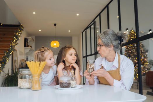 Grandmother and granddaughter are cooking on kitchen. Grandmother shares experience