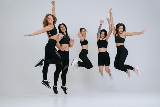 diverse models jump up, enjoying time together, look at camera having smile and natural unique beauty