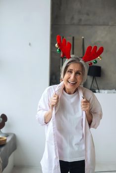 Grandma wearing deer christmas hat, happy smiling face looking at the camera. positive person.