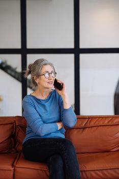 Image of senior woman talking on smartphone at home