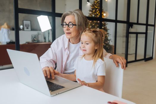 Child and granny looking at the camera with laptop at home