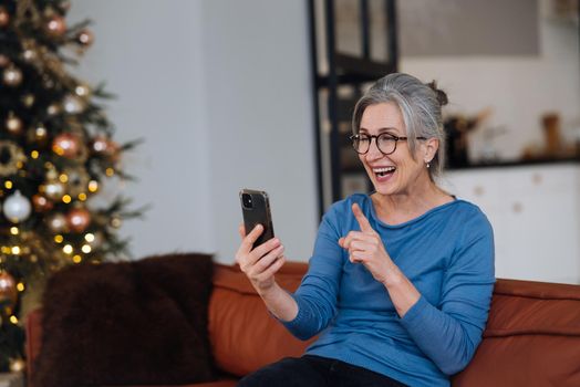 Happy smiley face senior elderly woman using smartphone video call conference camera and talking with family.Video chat social distancing.