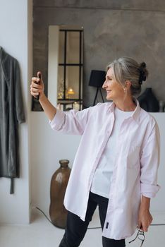 Close up photo of cheerful confident excited dreamy elderly female taking making self portrait