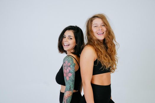 Two young women posing over white background. Two girlfriends, body positive concept
