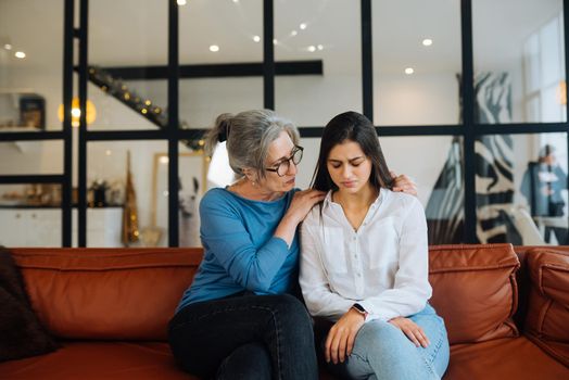 Grandmother comforting her sad granddaughter at home. Support concept