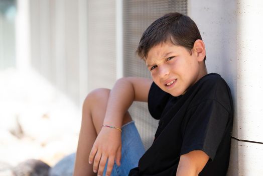 Portrait of handsome male child in the city outdoors. Natural light.