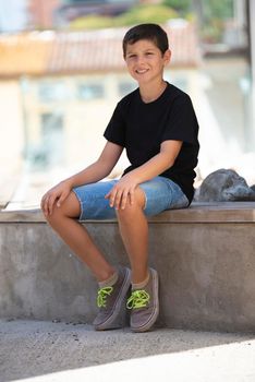 Portrait of handsome male child in the city outdoors. Natural light.