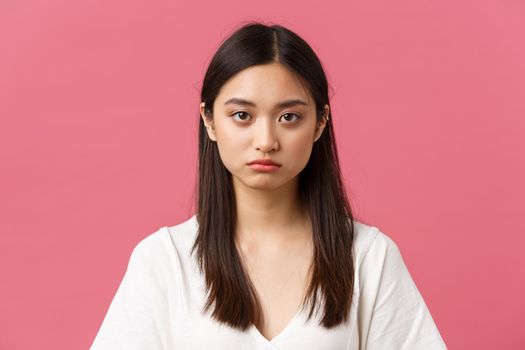 Beauty, people emotions and summer leisure concept. Close-up of gloomy and sad, tired young asian female employee looking at camera reluctant, standing distressed over pink background.