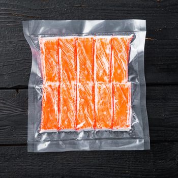 Crab stick surimi vacuum pack set, on black wooden table background, top view flat lay