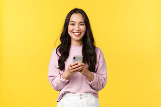 People emotions, lifestyle leisure and beauty concept. Smiling attractive young 20s woman using mobile phone. Girl making order from online shop using smartphone or using carsharing app.