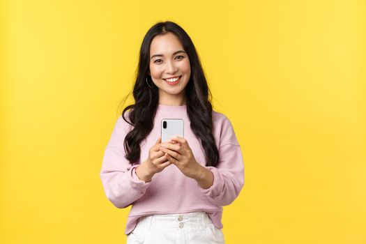 People emotions, lifestyle leisure and beauty concept. Kawaii smiling asian woman taking picture on smartphone, using photo filters to edit post in application, using mobile phone.