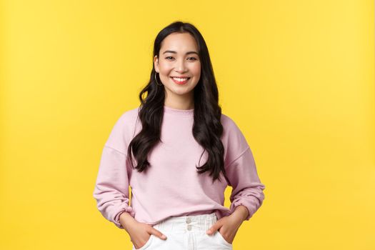 People emotions, lifestyle and fashion concept. Smiling cute asian girl in stylish clothes smiling camera, standing yellow background with happy expression, enjoying summer.