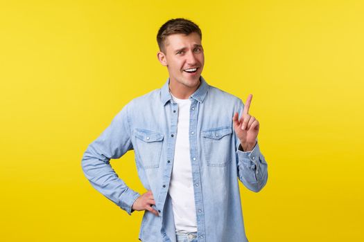 Cheerful smiling blond man shaking finger, tell not so fast, scolding someone or asking hold on, wait sec, standing yellow background upbeat, showing advertisement on top.