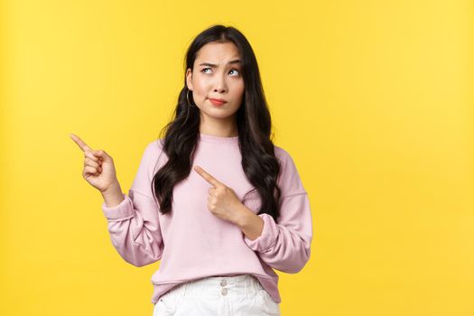 People emotions, lifestyle and fashion concept. Skeptical and doubtful modern asian woman in stylish outfit smirk disbelief and dislike as pointing upper left corner at bad advertisement.