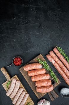 Fresh raw pork, beef and chicken sausages, top view with space for text, on black background.