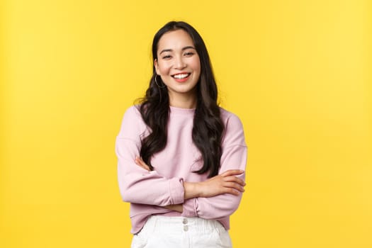 People emotions, lifestyle and fashion concept. Cheerful good-looking korean girl having fun, laughing out loud and feeling happy, standing joyful over yellow background.