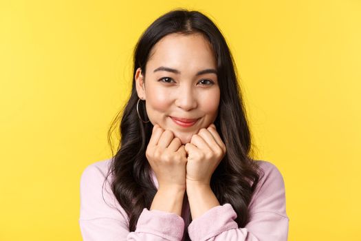 People emotions, lifestyle leisure and beauty concept. Lovely asian woman smiling at camera and looking sympathy, affection, feeling joy and love, advertise shop, stand yellow background.