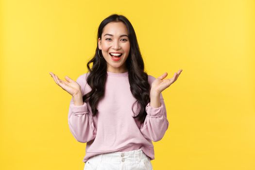 People emotions, lifestyle and fashion concept. Happy pleased cute korean girl in casual outfit, clasp hands and laughing, applause over fantastic performance, praise good job, yellow background.