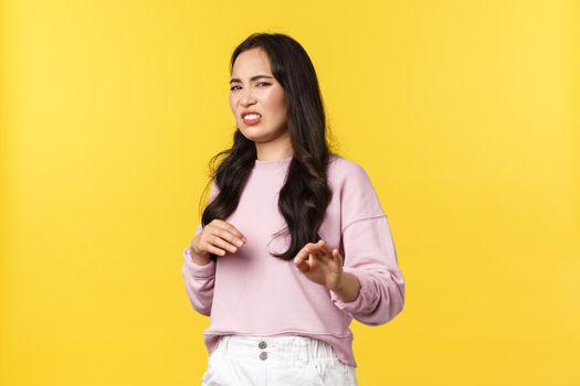 People emotions, lifestyle and fashion concept. Gross stay away from me. Disgusted picky and arrogant asian woman gesturing and step back with aversion, rejecting offer, refusing, yellow background.