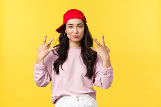 People emotions, lifestyle leisure and beauty concept. Stylish and cute hip-hop dancer girl, showing swag gesture and smirk sassy, acting confident and cool, standing yellow background.
