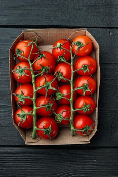 Ripe cherry tomatoes in tray, on black wooden table, top view