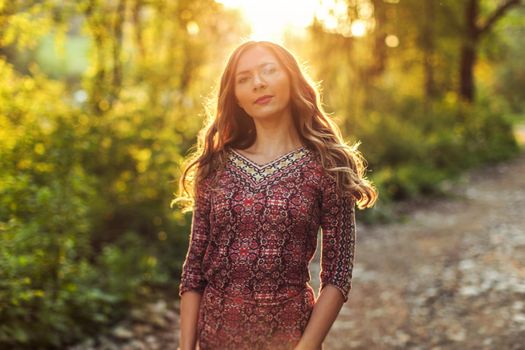 Young woman wearing dress, in forest backlight by sunset light.