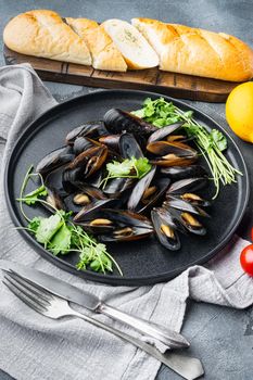 Steamed mussels in white wine set, on plate, on gray background