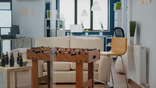 Empty space prepared for after work drinks with workmates. Nobody in office with foosball game table for soccer, bottles of beer and snacks, meeting for fun activity after hours.