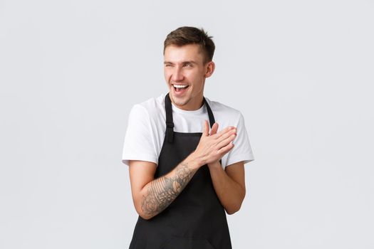 Small business owners, coffee shop and staff concept. Devious and smart funny barista in black apron, cafe worker rubbing hands as expect relish or satisfaction from accomplished plan, grinning sly.