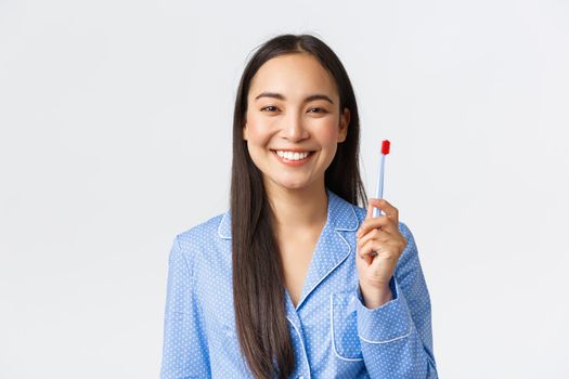 Close-up of happy smiling girl showing white teeth after brushing them with toothbrush in morning, standing pleased with new toothpaste flavour standing white background.