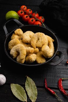 Uncooked shrimps in cheese breading set, on black wooden table background