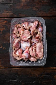 Raw poultry stomachs in plastic pack set, on old dark wooden table background, top view flat lay