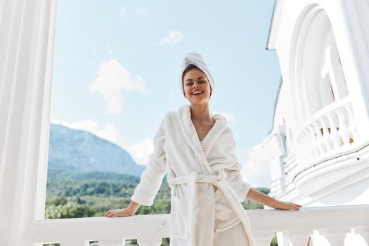 pretty woman in a white robe on the balcony bit on green nature unaltered. High quality photo