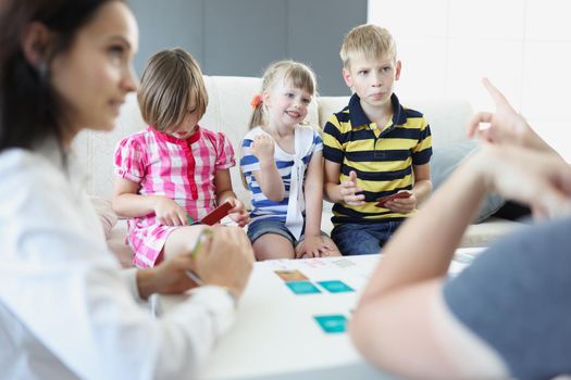 Portrait of cheerful children playing card game with parents at home. Adults teach kids how to play. Pastime, education, development, family time concept