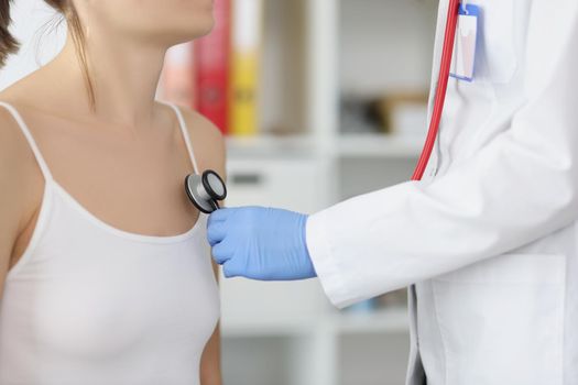 Close-up of female doctor listen to patient chest with stethoscope tool. Concentrated medical worker examine body, diagnostic. Medicine, healthcare concept