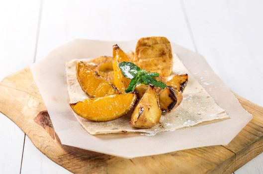 Fruits grilled with mint close up on a wooden board on white table. Takeaway composition