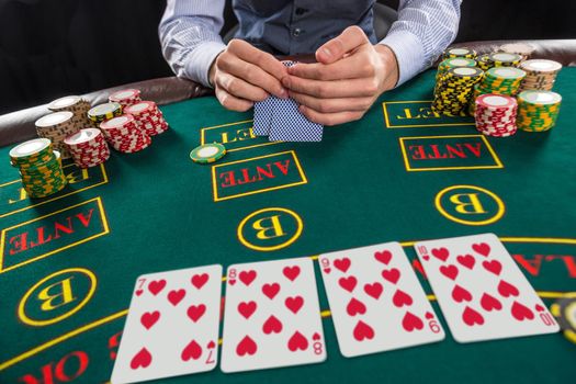 Close up of poker player with playing cards and chips at green casino table