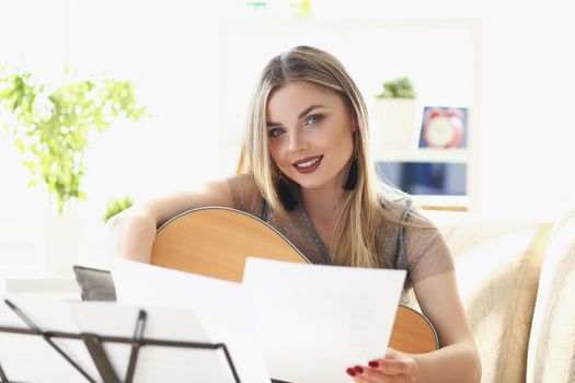 Portrait of pretty woman music composer, blonde with makeup look at camera. Notes on music stand in front. Concert, musical performance, rehearsal concept