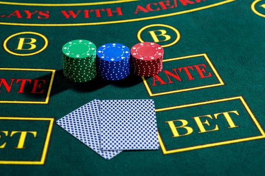 Poker play. Chips and cards on the green table