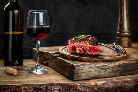 Grilled ribeye beef steak with red wine, herbs and spices on wooden table. Still life