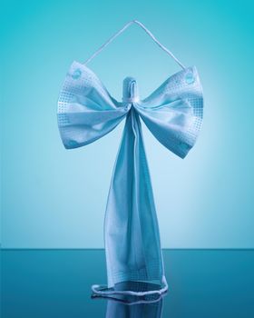 Blue antiviral medical respiratory protection face mask in the form of an angel on a blue background